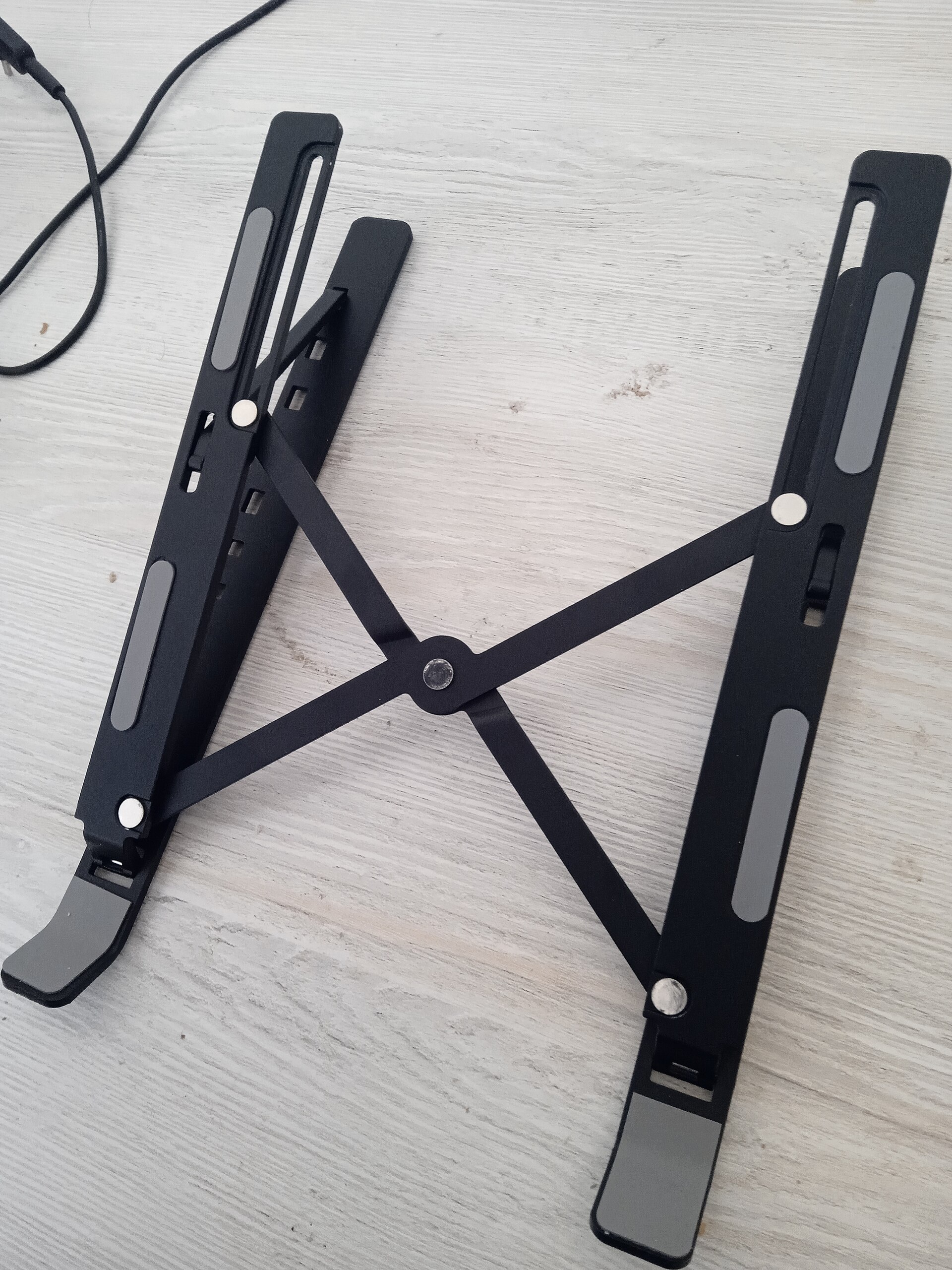Foldable laptop stand raising a laptop screen to eye level to prevent neck pain