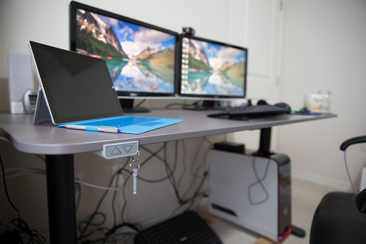 Adjustable sit-stand desk with dual monitors in a home office