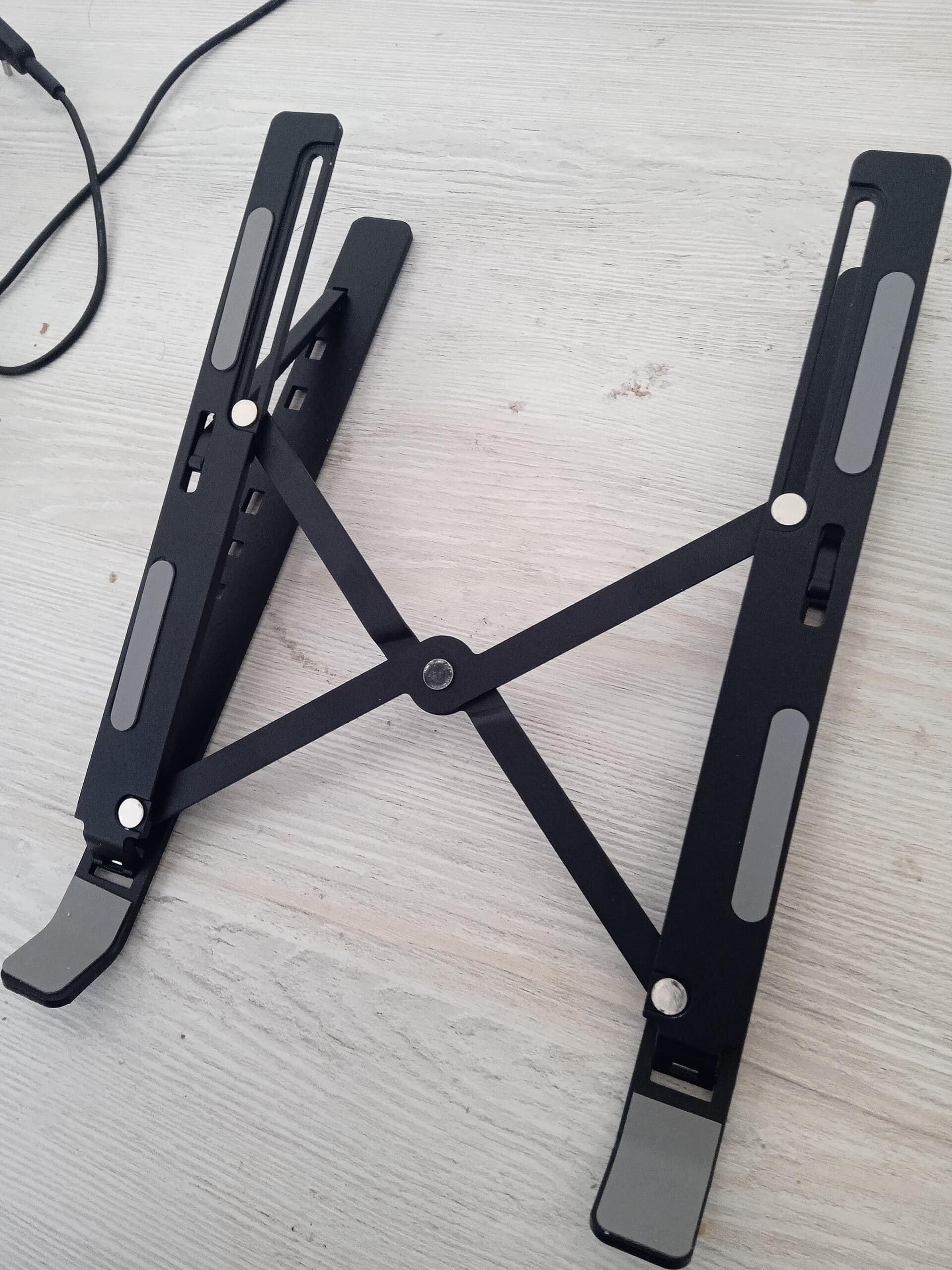 Folding aluminum laptop stand holding a 14-inch laptop on a small white desk