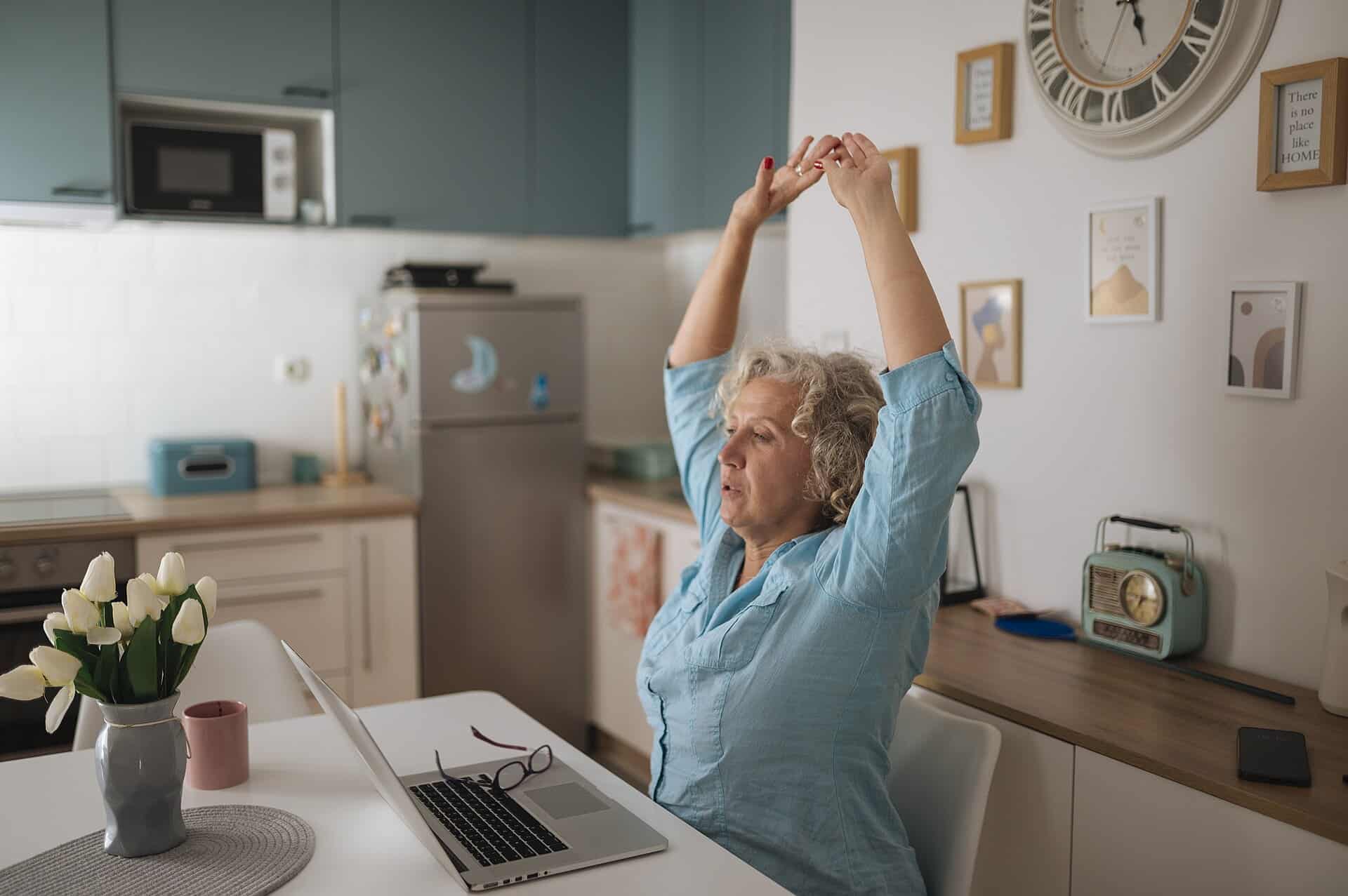 Woman stretching her arms while working on a laptop