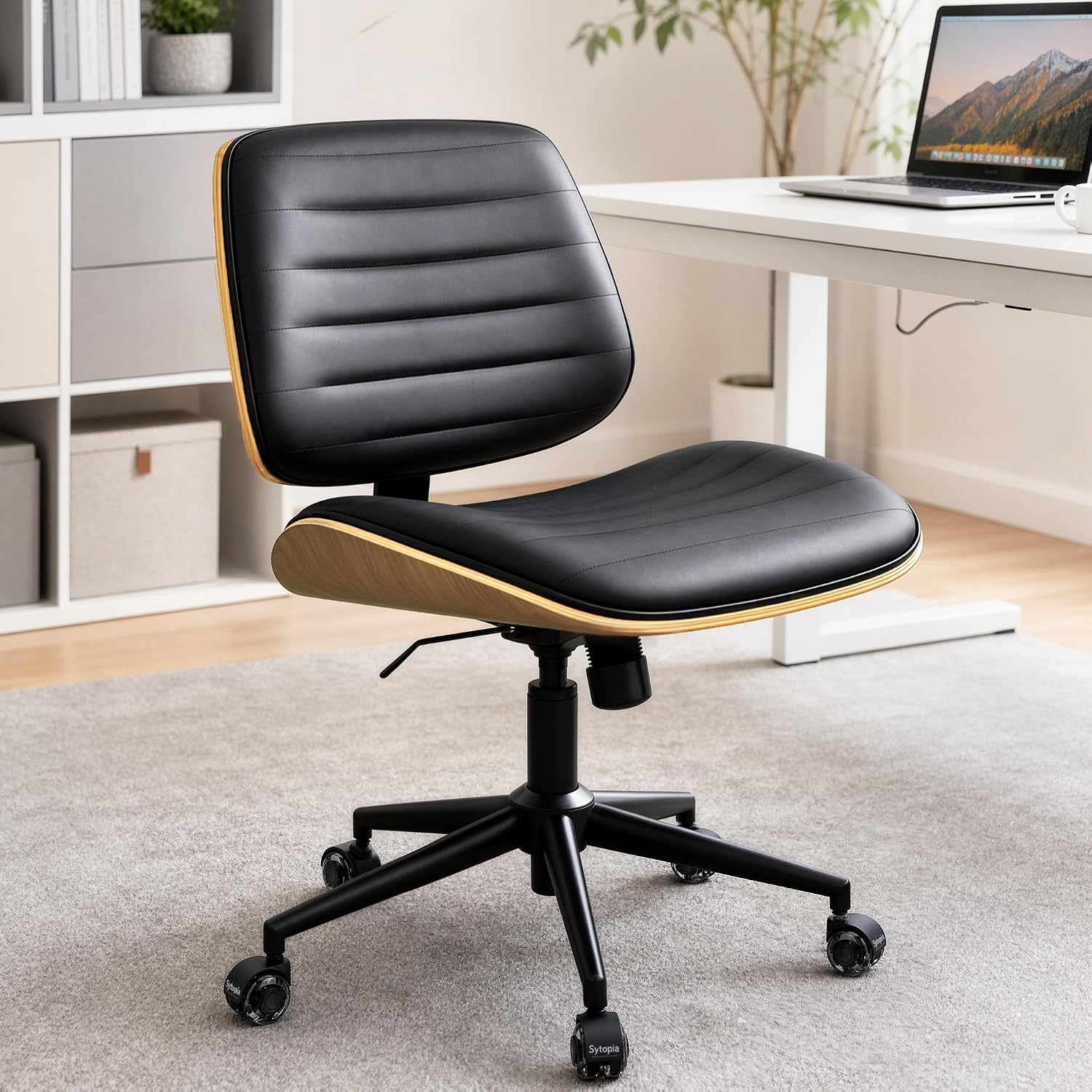 Sytopia small armless vintage black leather desk chair with walnut shell back beside a compact desk